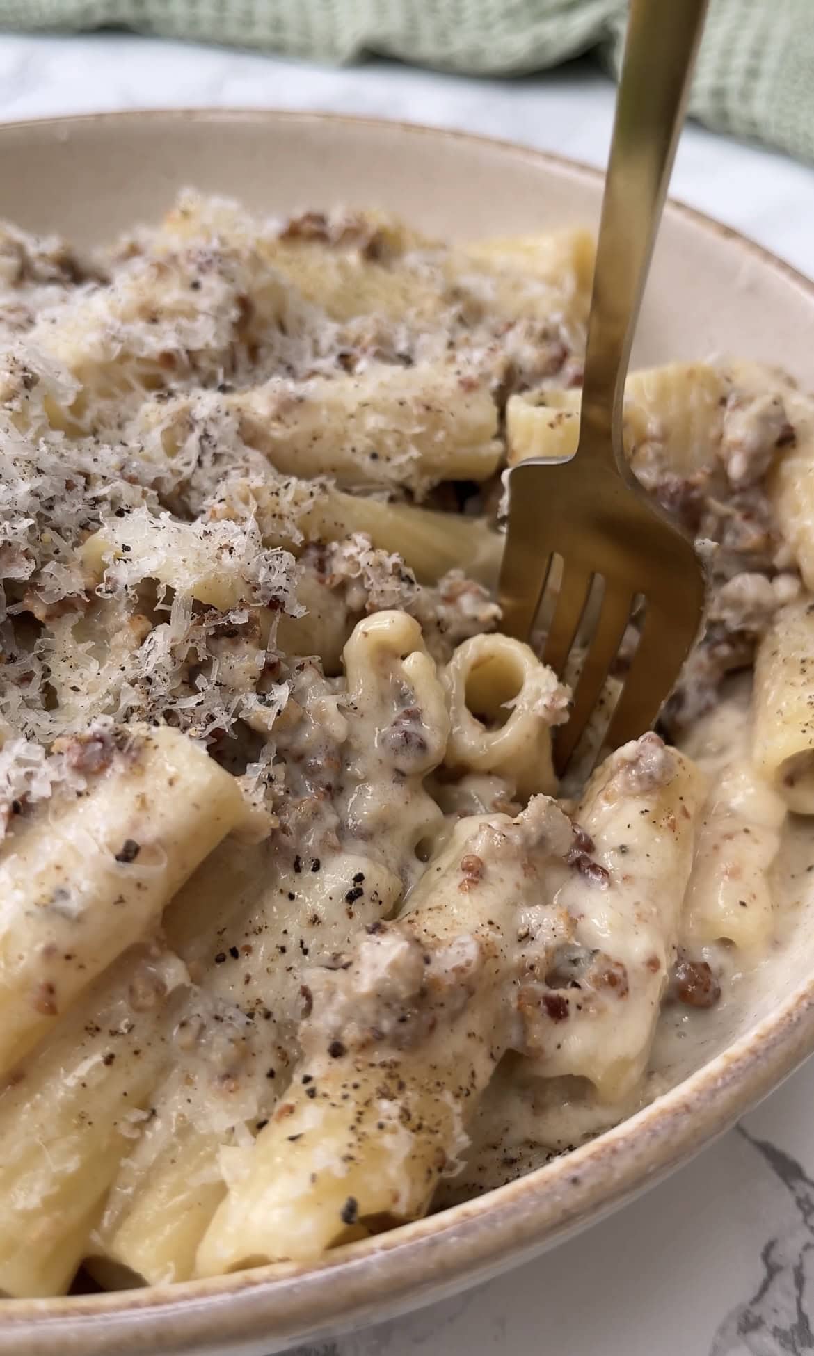 fork spearing creamy sausage pasta.