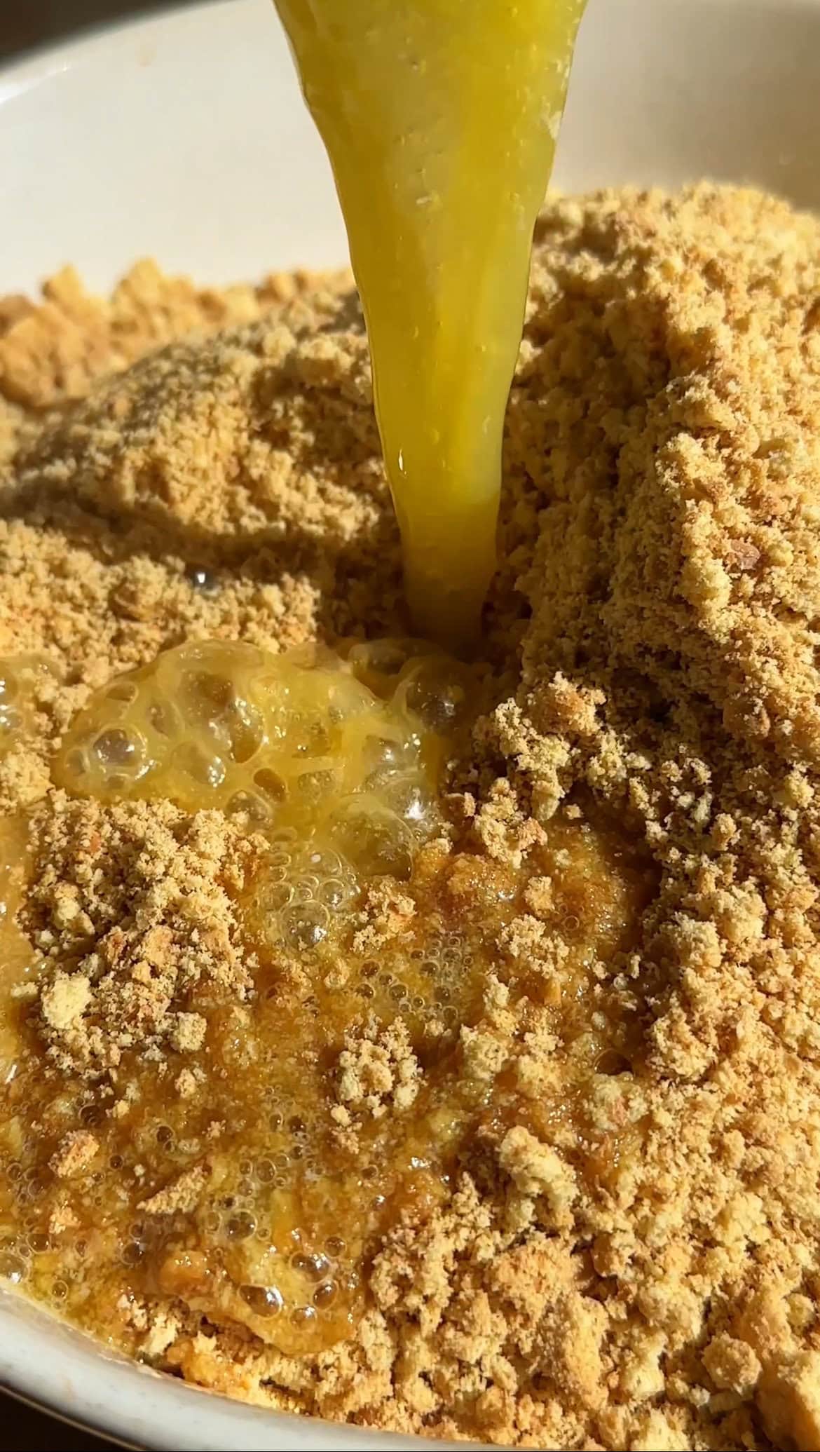 adding melted butter into biscuit crumbs.