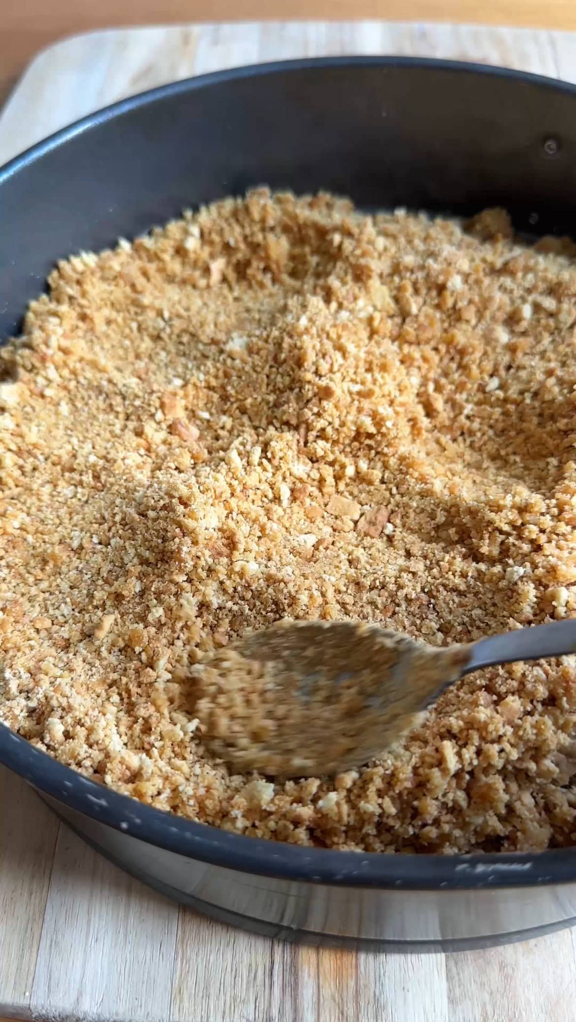 smoothing biscuit crumbs into the base of the tin.