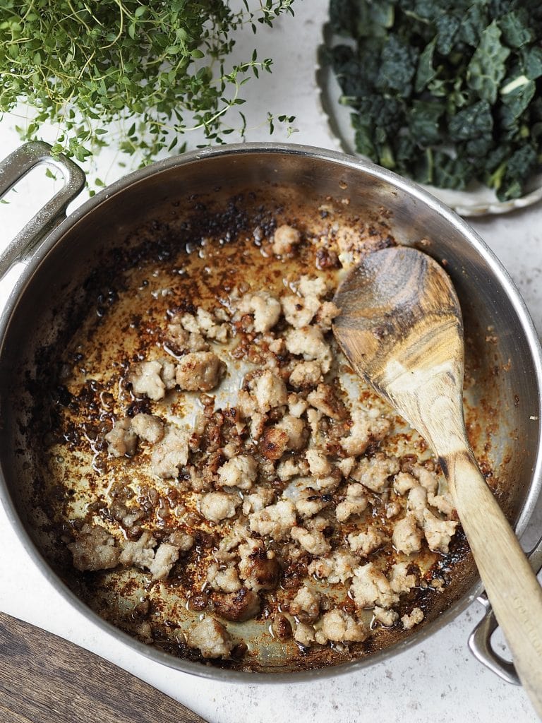 Sausage pieces being caramalised in a frying pan.