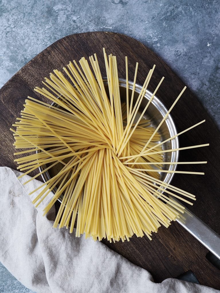 Dry linguini added to a saucepan.