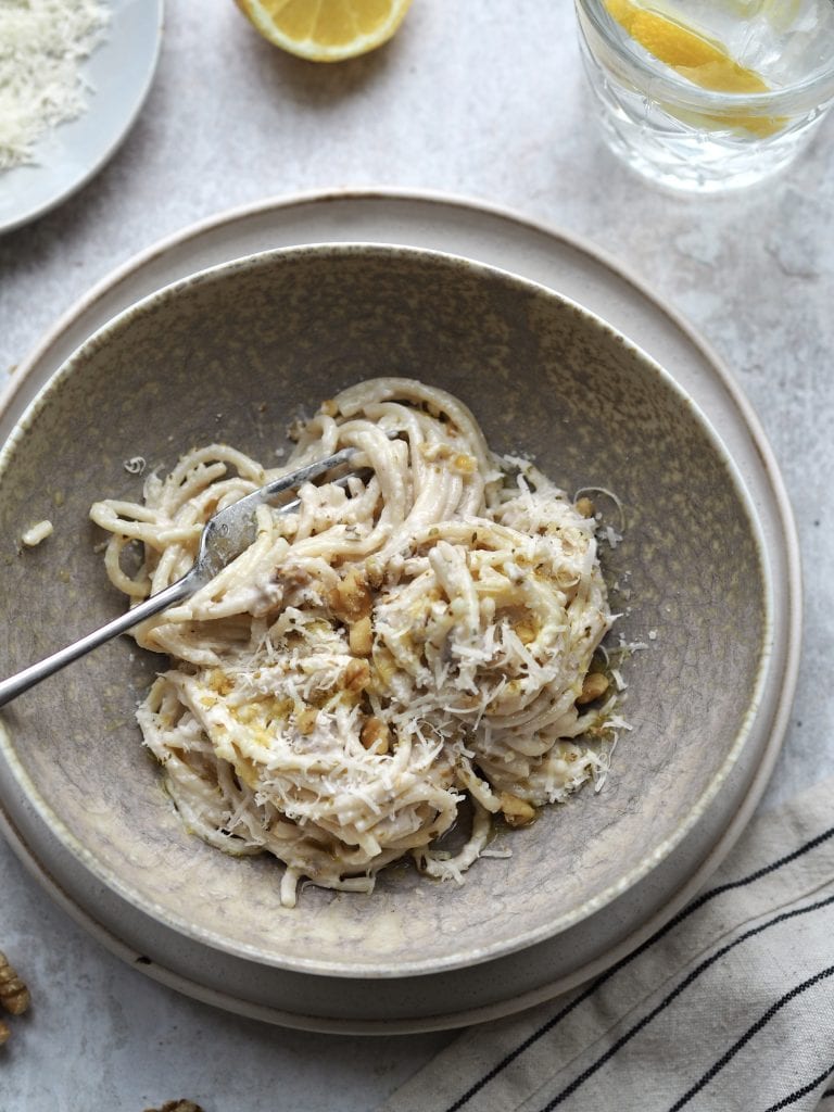 Close up of white pesto pasta in a grey bowl.