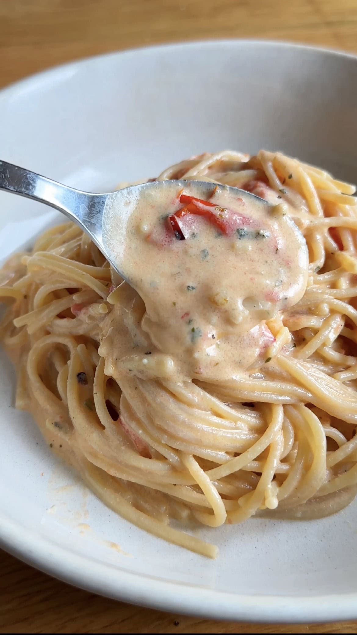 spooning creamy sauce over the boursin tomato pasta