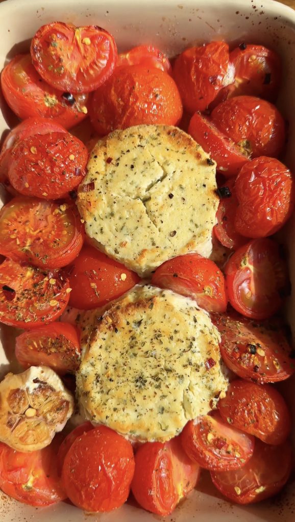 roasted boursin and tomatoes with head of garlic in a roasting tin