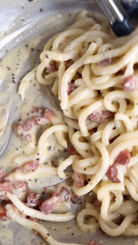 mixing the creamy udon carbonara