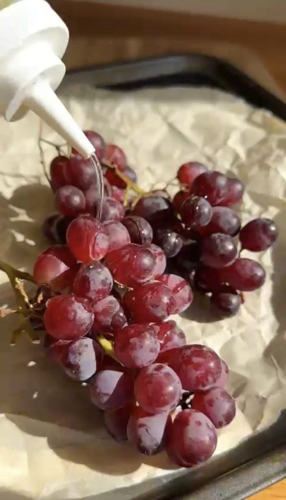 Drizzling grapes with olive oil before roasting