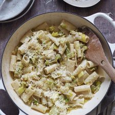 White shallow casserole dish of rigatoni tossed with cream and caramalised leeks and topped with grated cheese.