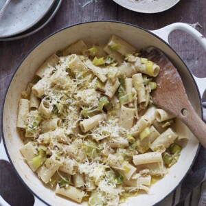 White shallow casserole dish of rigatoni tossed with cream and caramalised leeks and topped with grated cheese.