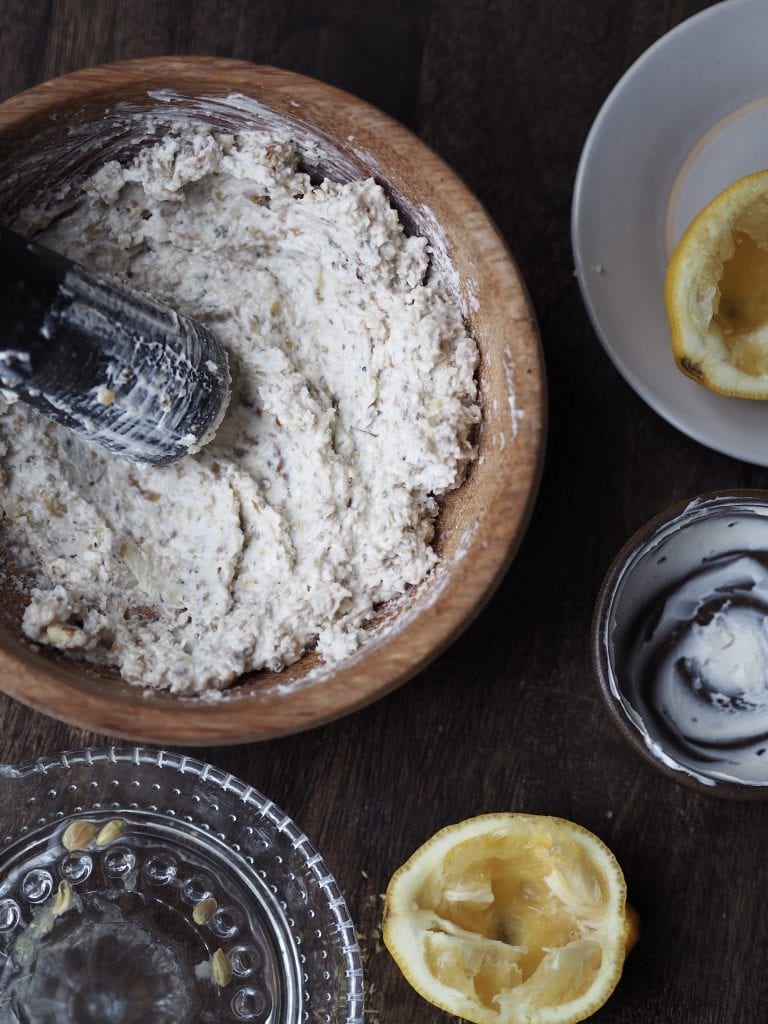 White pesto being made in a wooden mortar and pestle.