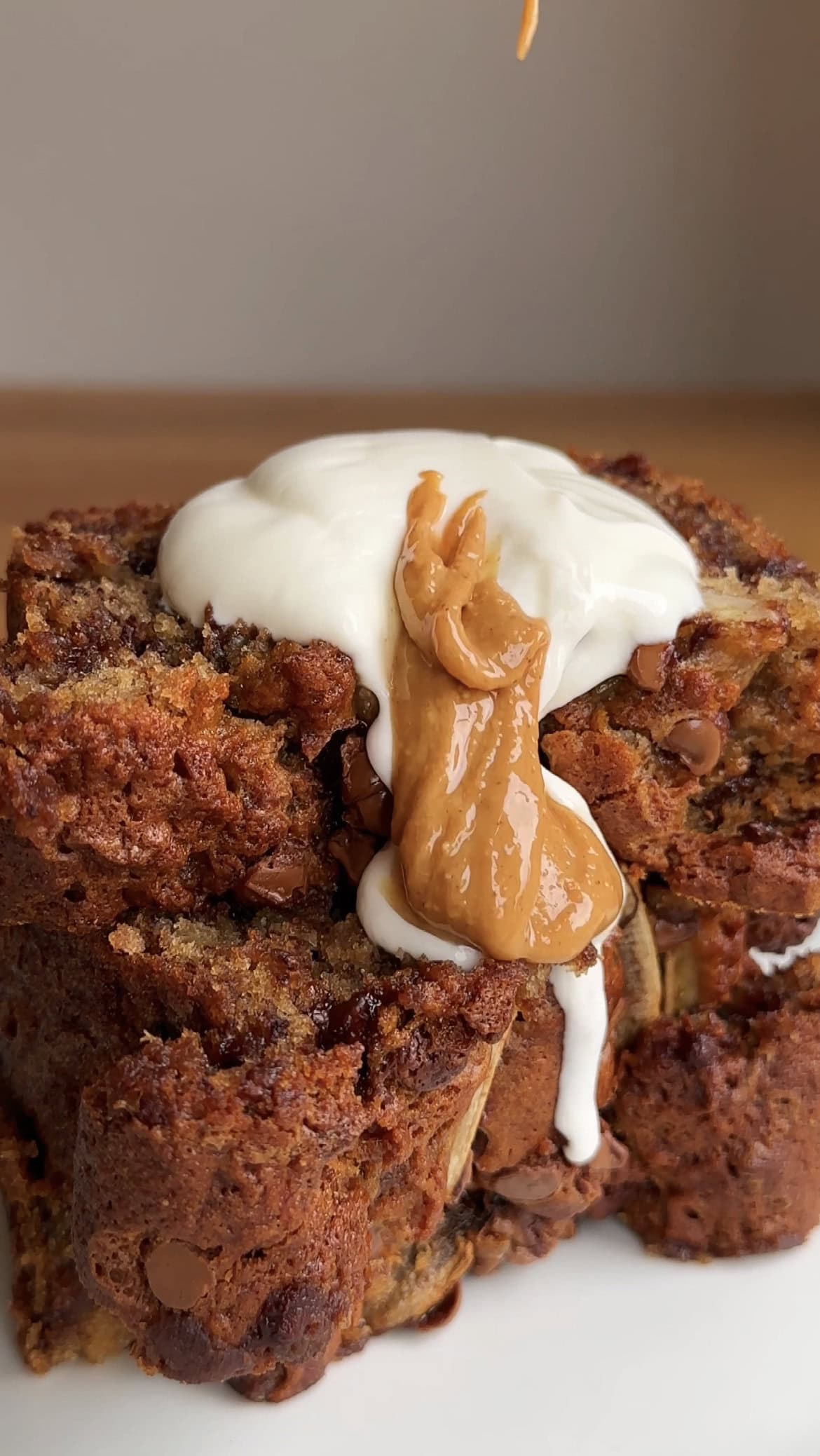 a spoon of yoghurt and peanut butter on slices of chocolate chip banana bread