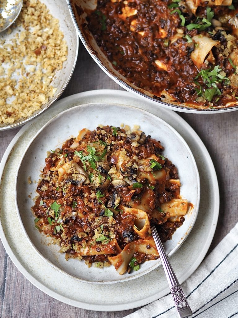 Lentil bolognese and pasta in a white bowl. 