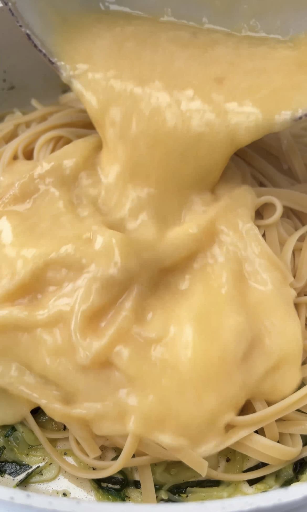 pouring eggs into pasta.