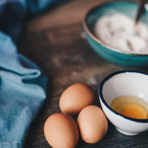 eggs and a bowl of flour on a wooden board