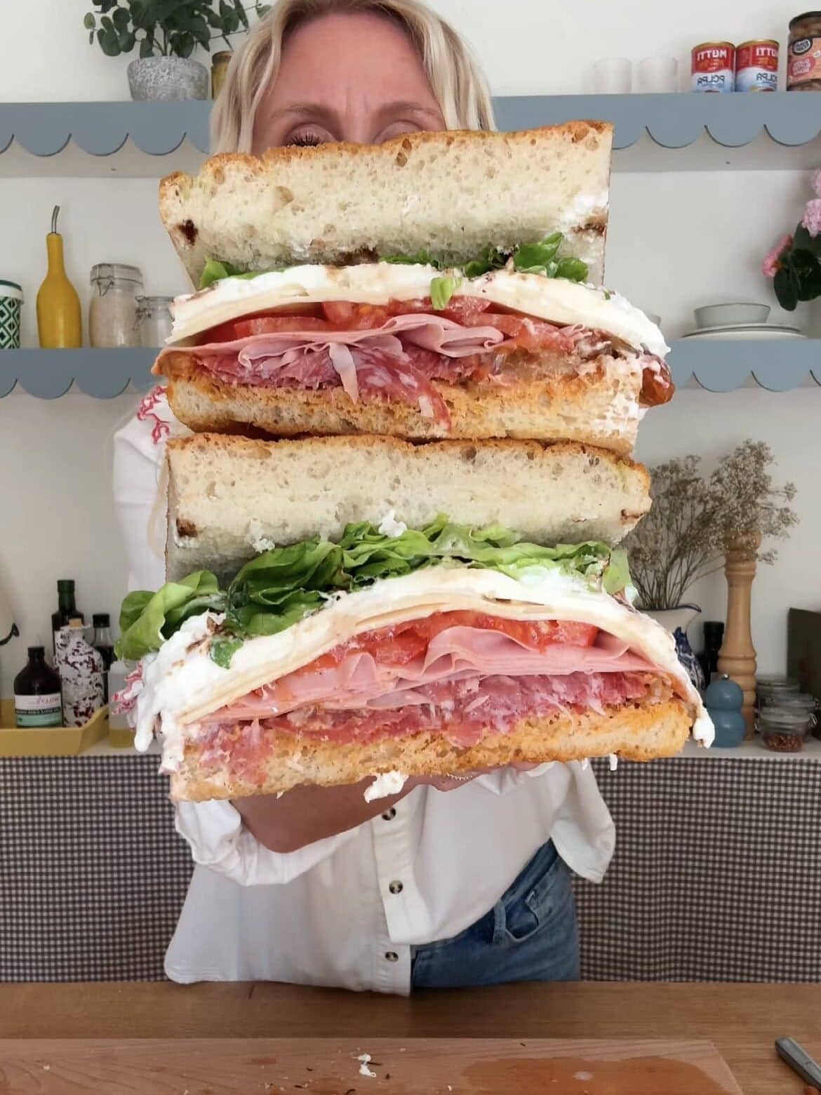 woman holding salami burrata sandwich to the camera