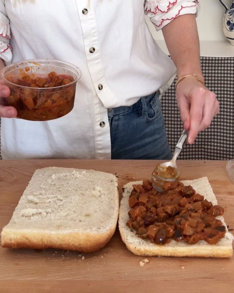 woman spreading aubergine caponata on focaccia with a silver spoon