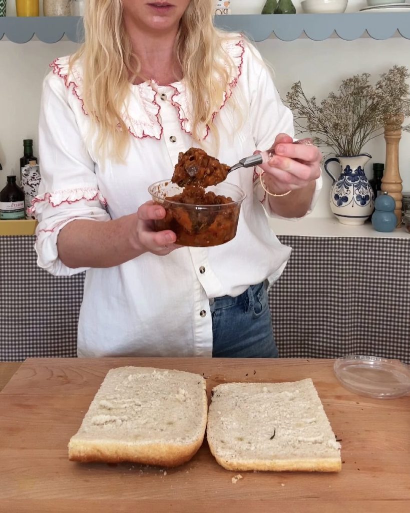 woman holding a tub of aubergine caponata