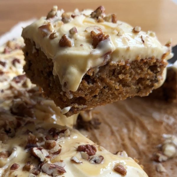 lifting a slice of carrot sheet cake from the pan