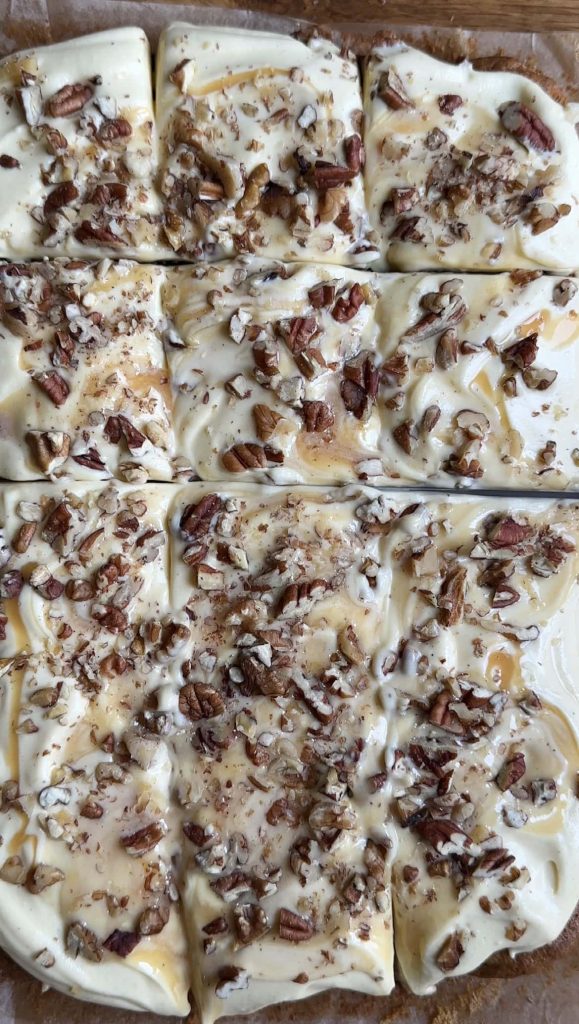 carrot sheet cake covered with icing with a knife cutting through