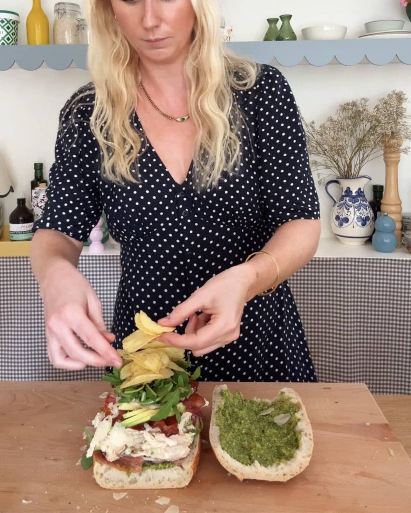 woman adding crisps to chicken bacon sandwich