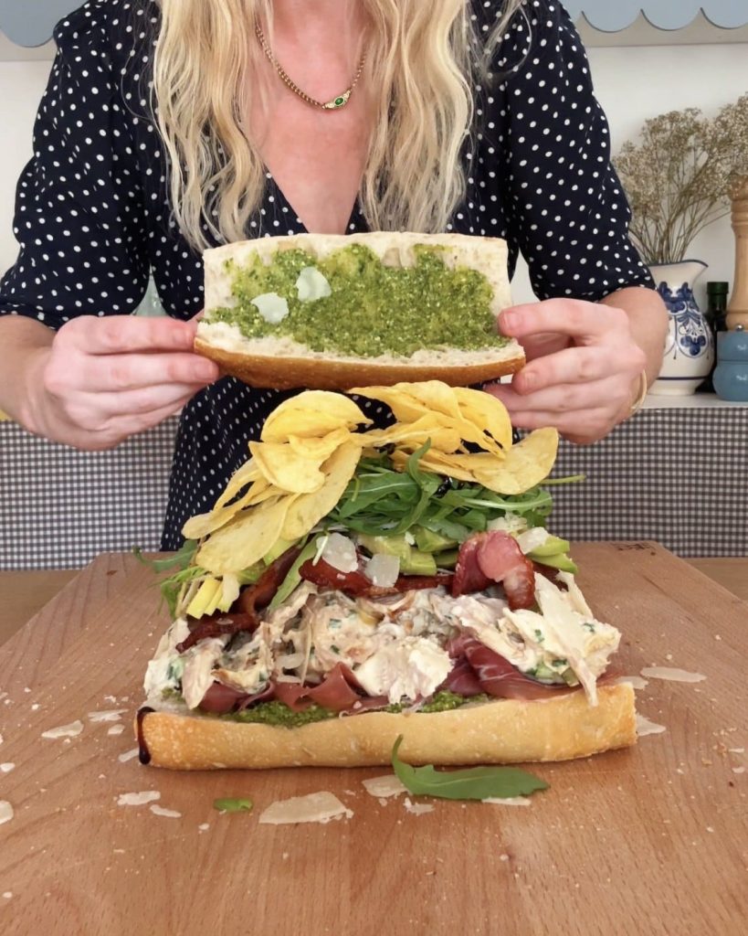 woman adding top of bread to chicken bacon sandwich