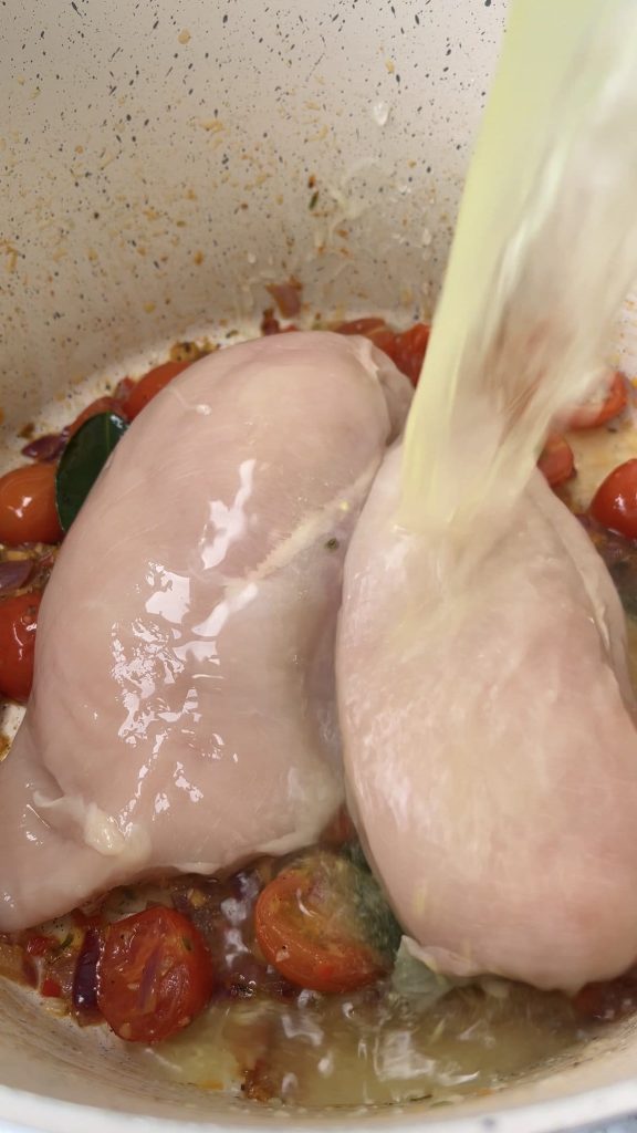 Adding stock to the saucepan on chicken breasts for Thai Chicken Soup With Rice