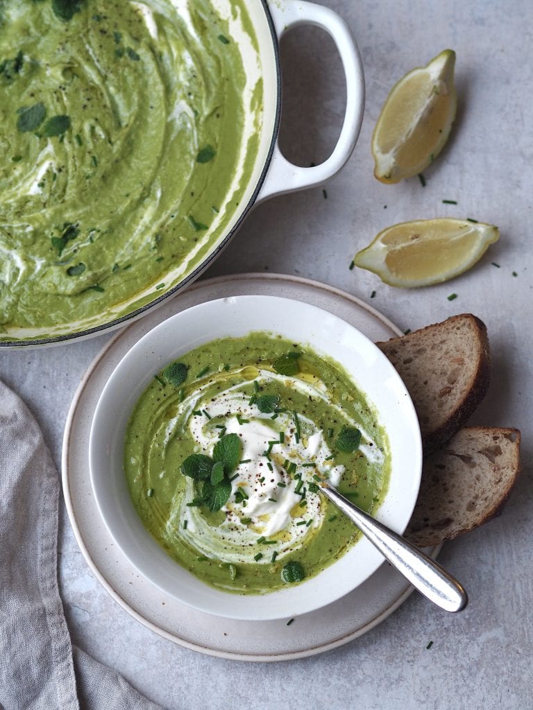 little gem, pea, mint soup in a white bowl with a pan of soup next to it