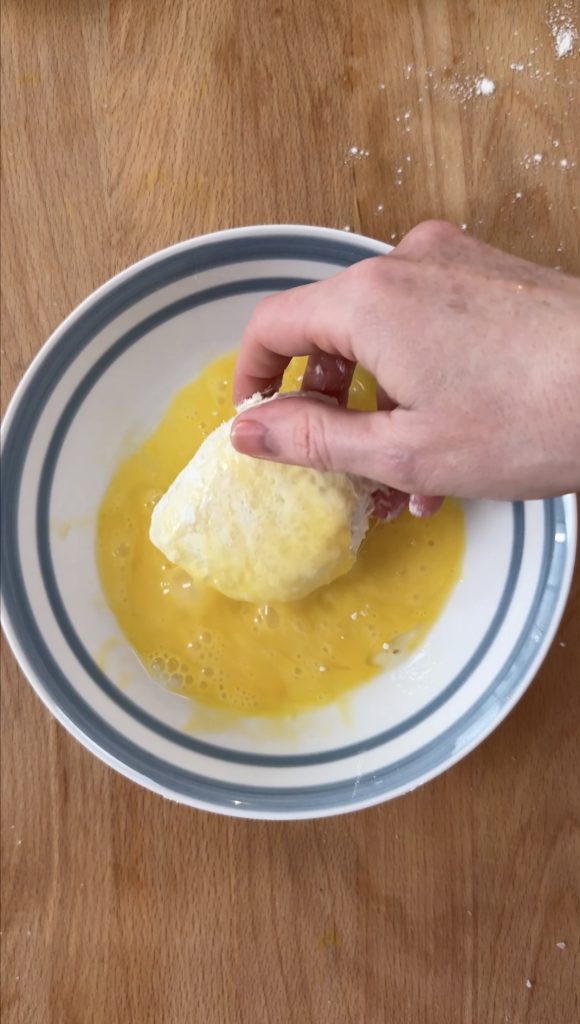 woman coating mozzarella in egg