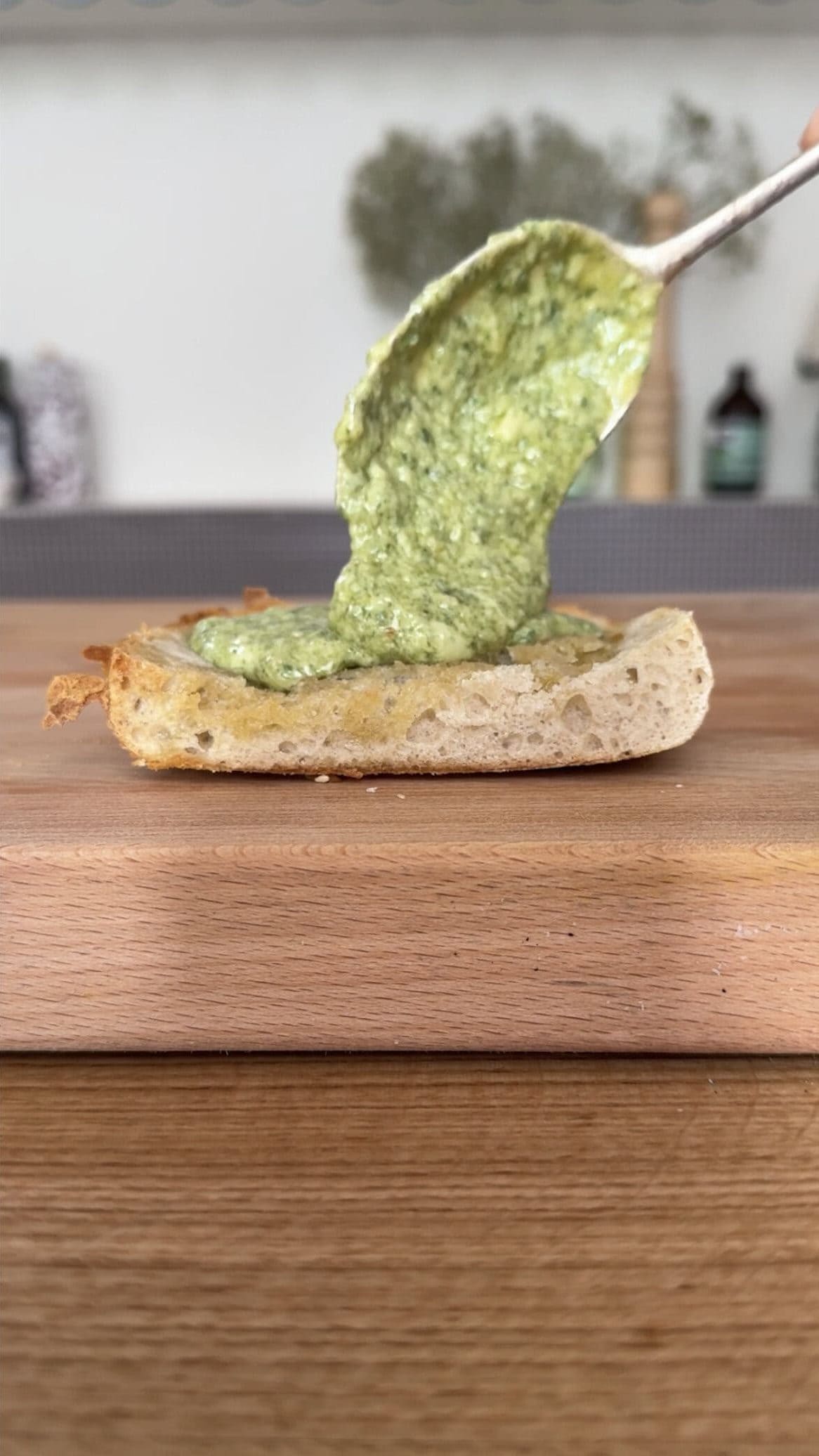 spooning pesto onto a slice of bread