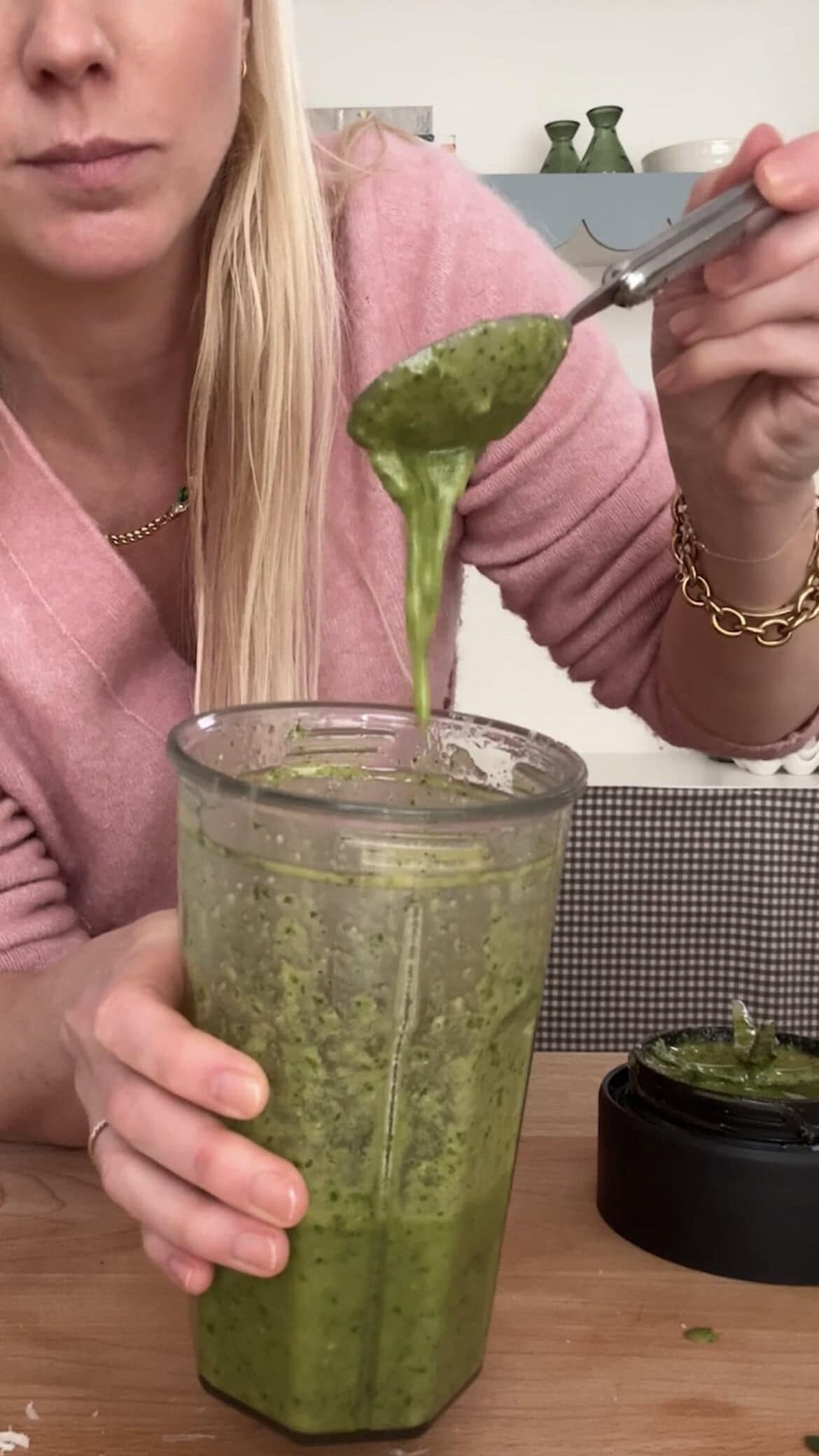 woman spooning pesto out of a blender