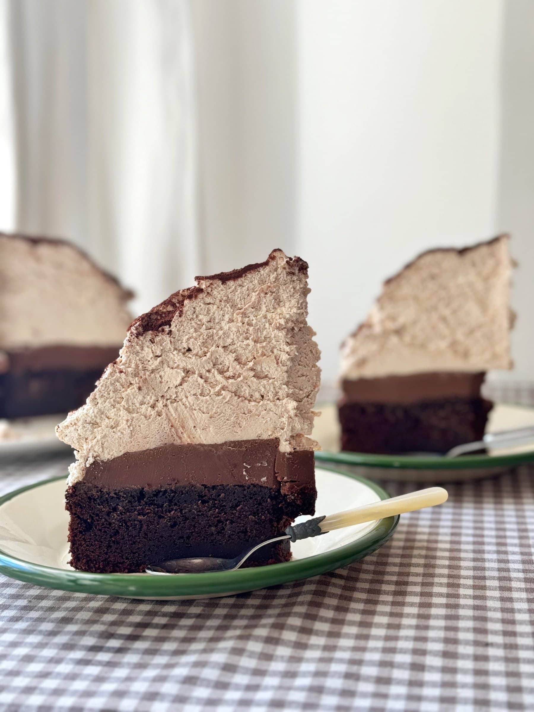 slice of chocolate mud cake with malted whipped cream stood on a green plate