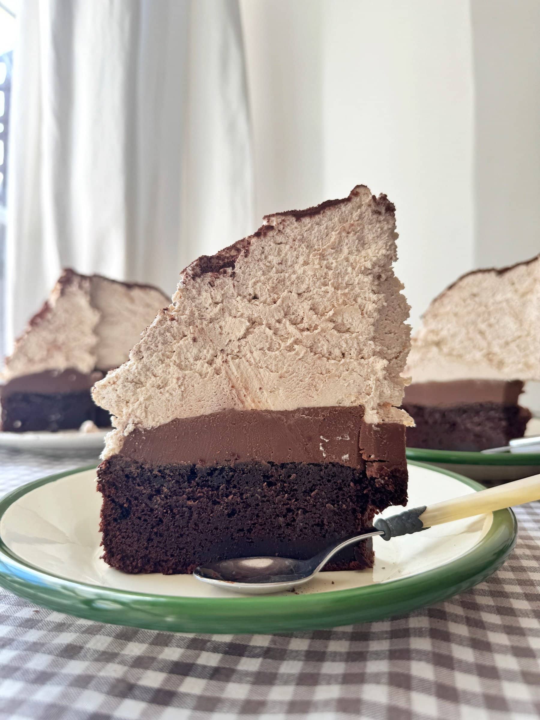 slice of chocolate mud cake with malted whipped cream stood on a green plate