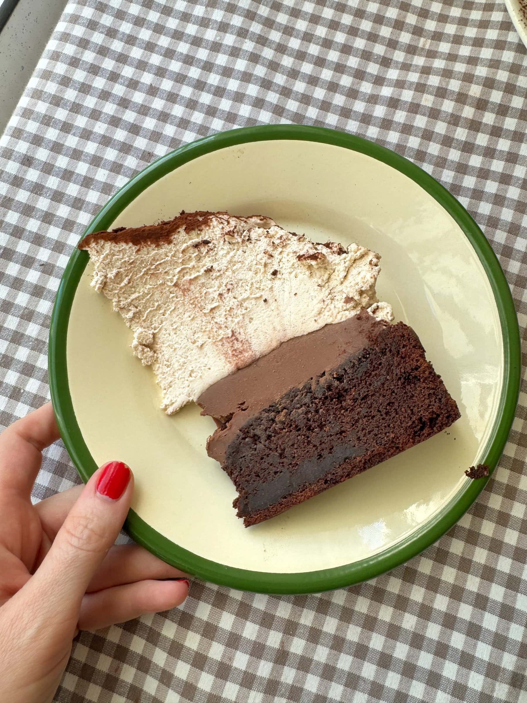 slice of chocolate mud cake with malted whipped cream on a green plate