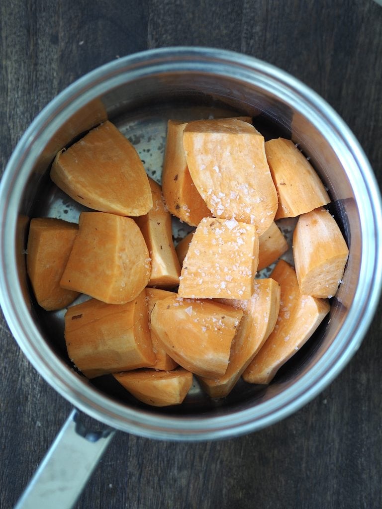 Diced sweet potatoes in a saucepan with flaky sea salt.