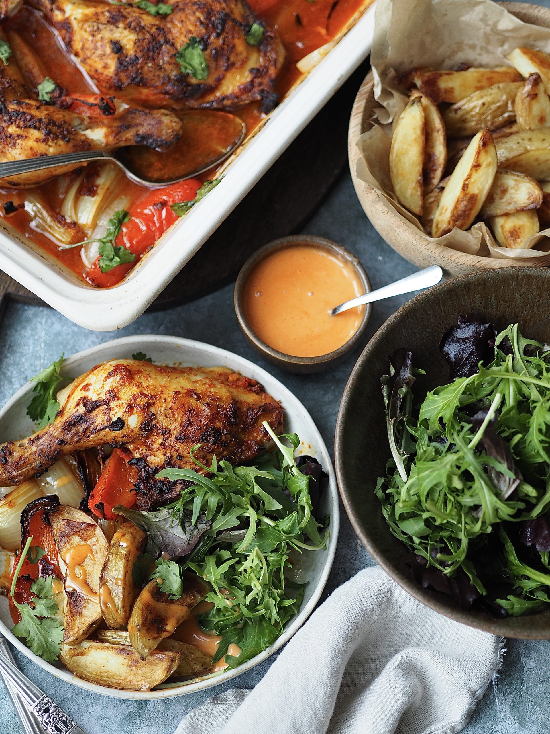 Peri Peri Chicken being plated up with potato wedges, salad and sriracha mayonnaise.