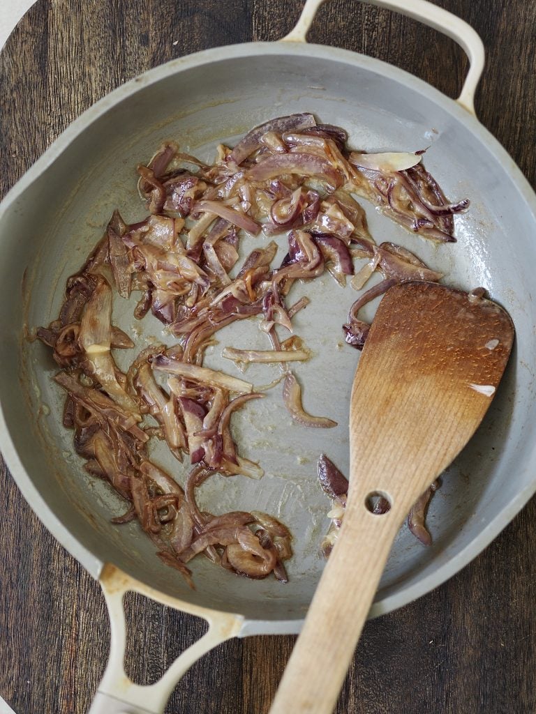 Fried red onions in a grey frying pan.