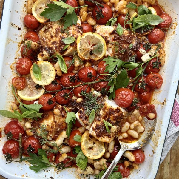 White tray of roasted tomatoes, beans and harissa cod.