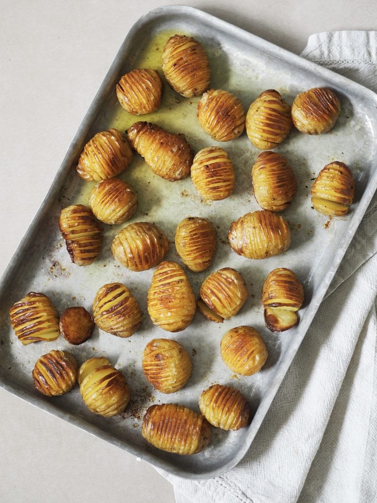 Roasted hasselback potatoes on a baking sheet.