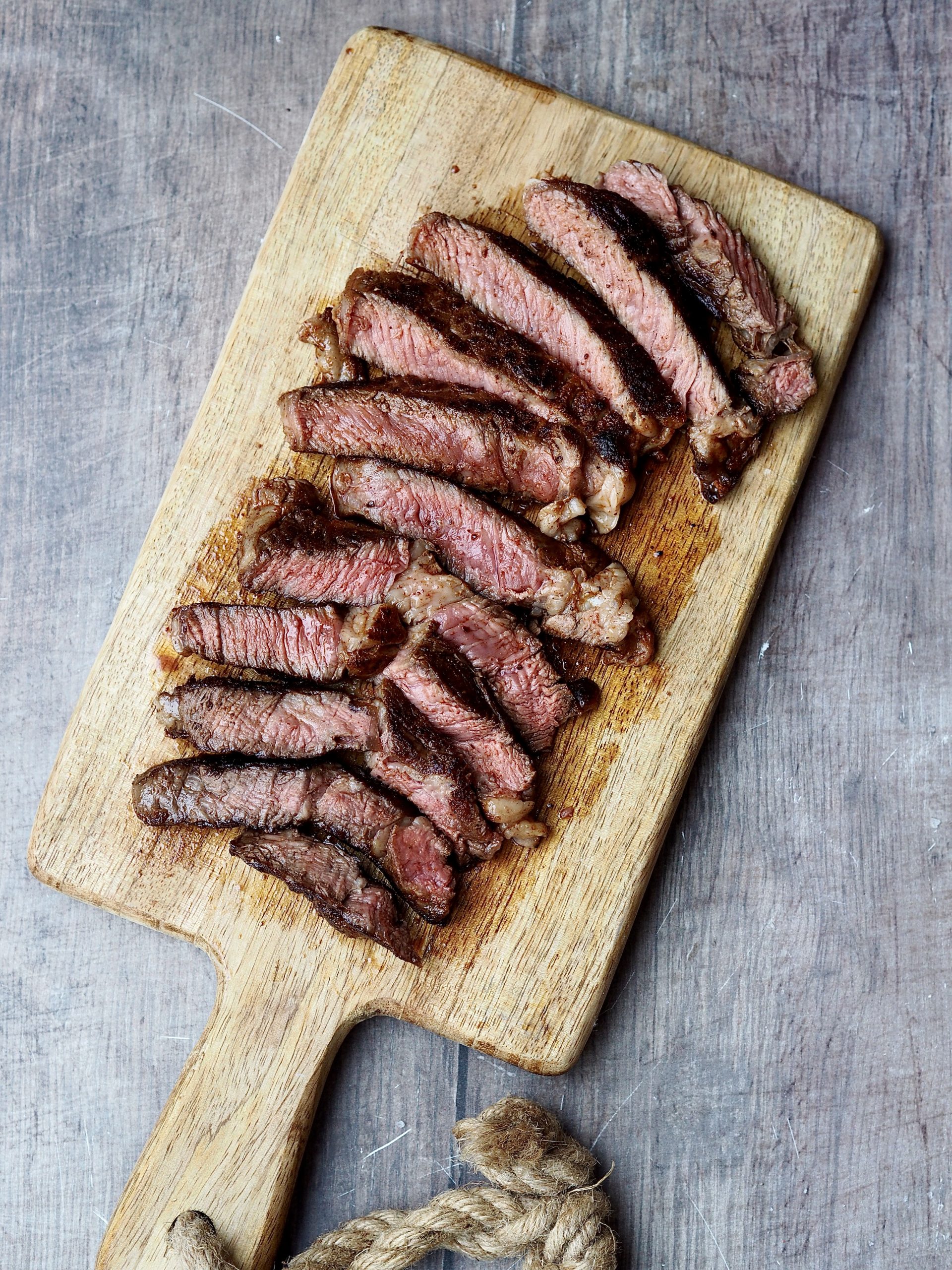 Sliced rib eye steak on a wooden serving board.