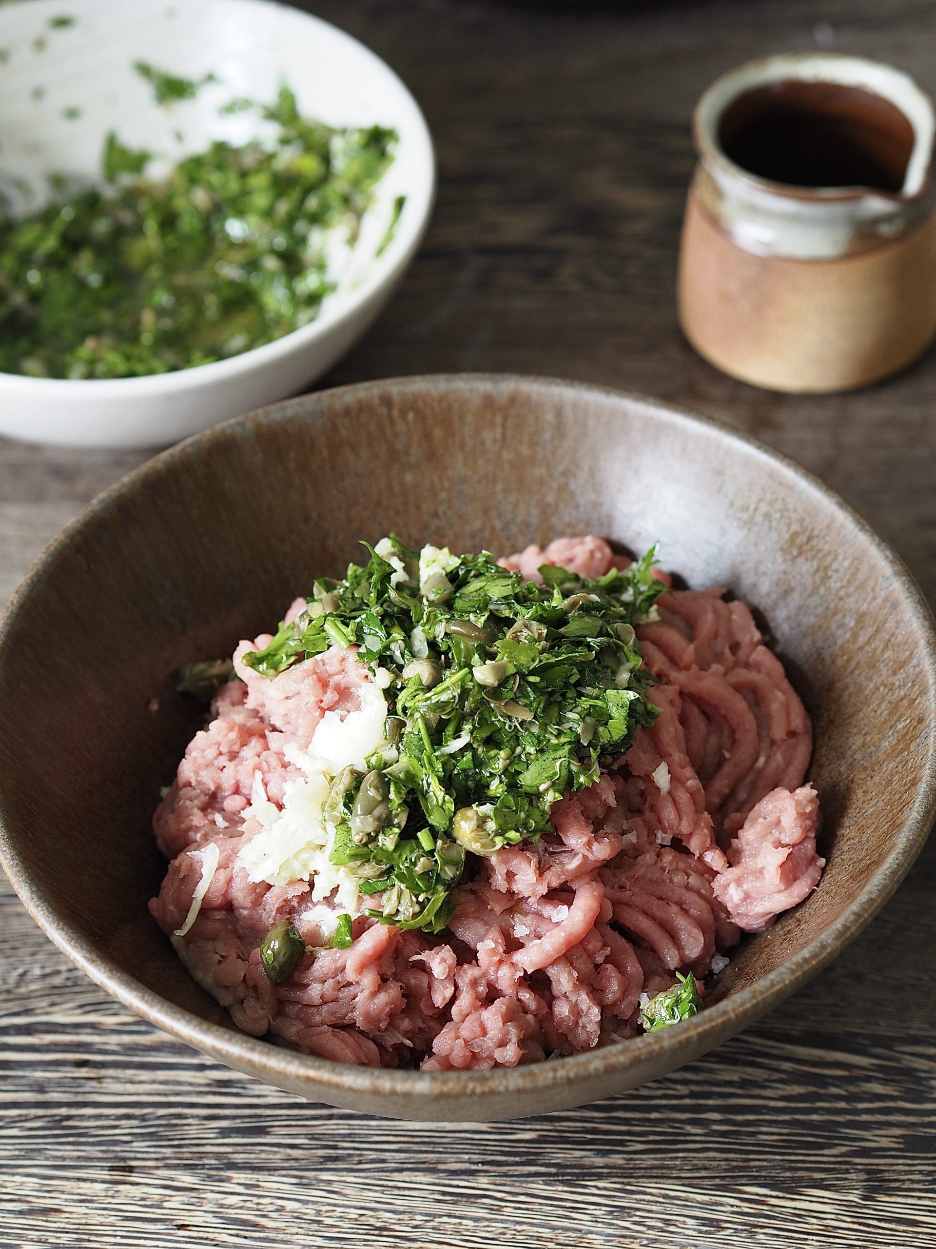 Salsa verde on top of a bowl of raw chicken mince.