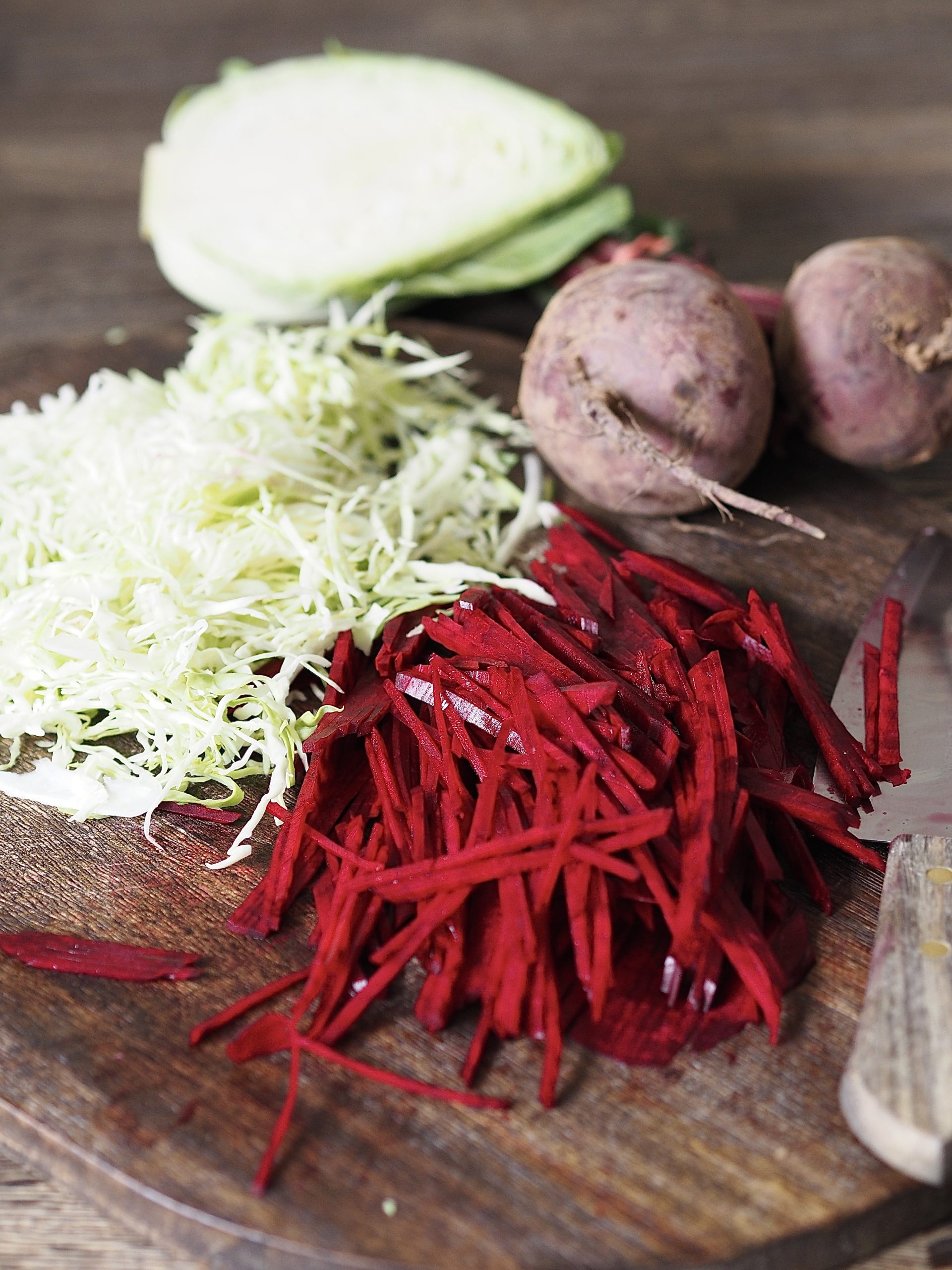 Sliced cabbage and beetroot on a wooden cutting board.