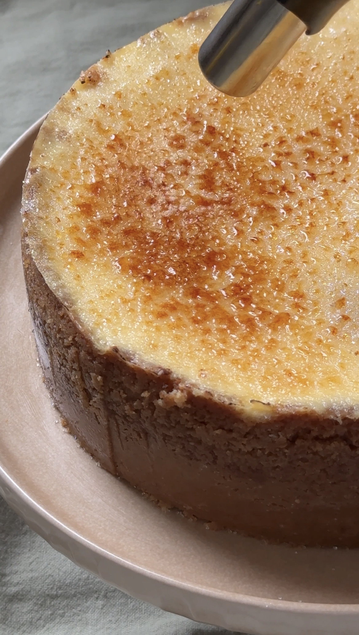 using a blow torch to caramelise the sugar on the top of creme brulee cheesecake