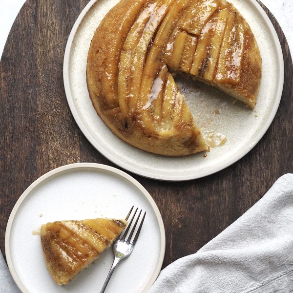 upside down banana cake on a white plate with a slice out