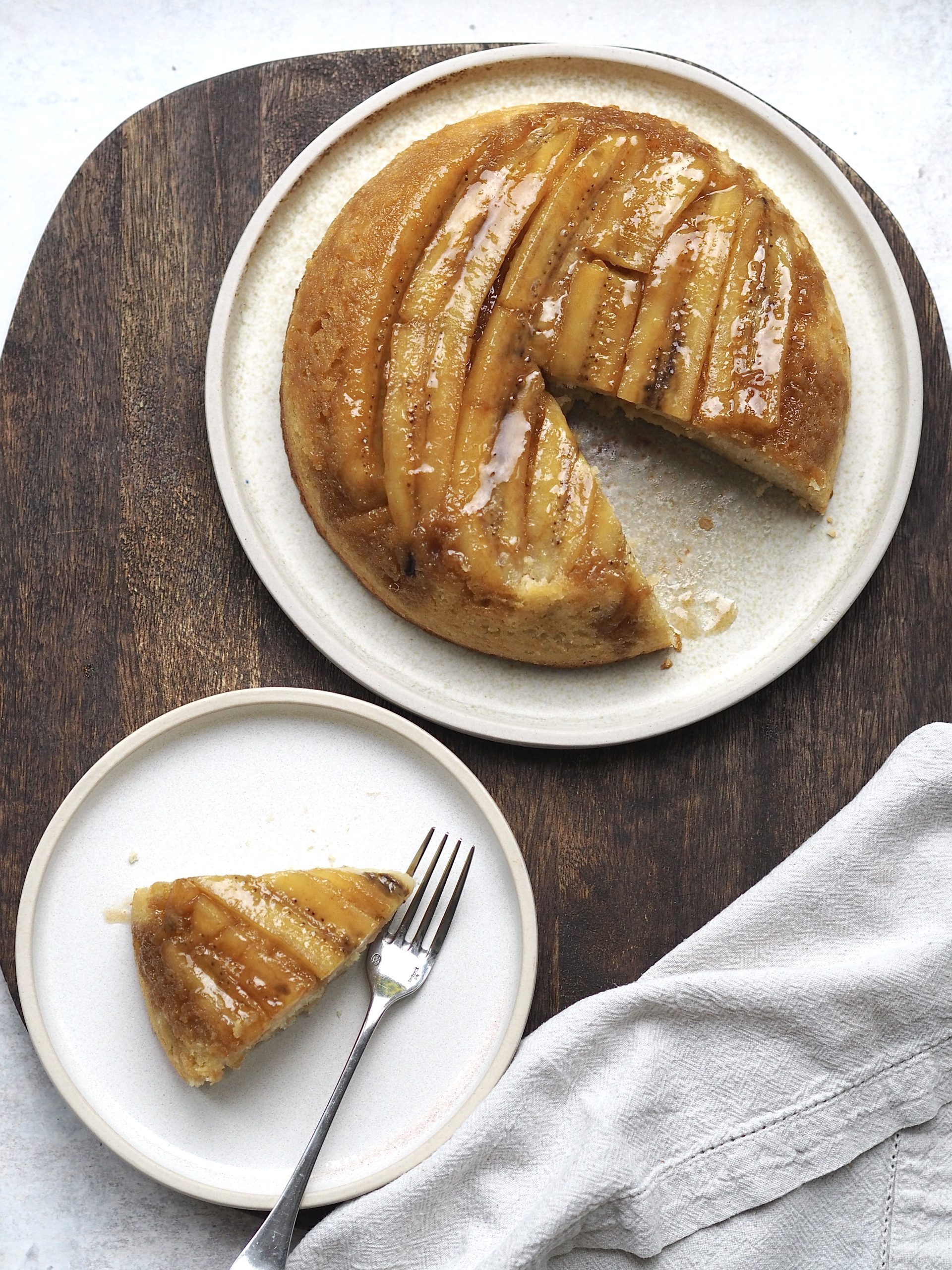 upside down banana cake on a white plate with a slice out