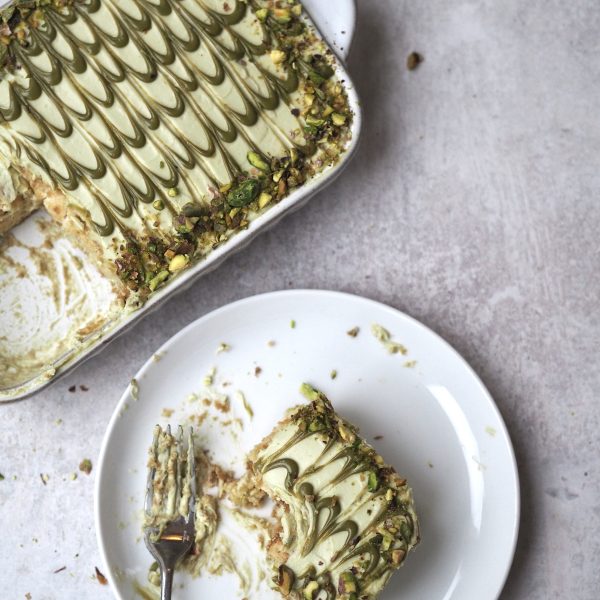 pistachio tiramisu in white dish with slice removed