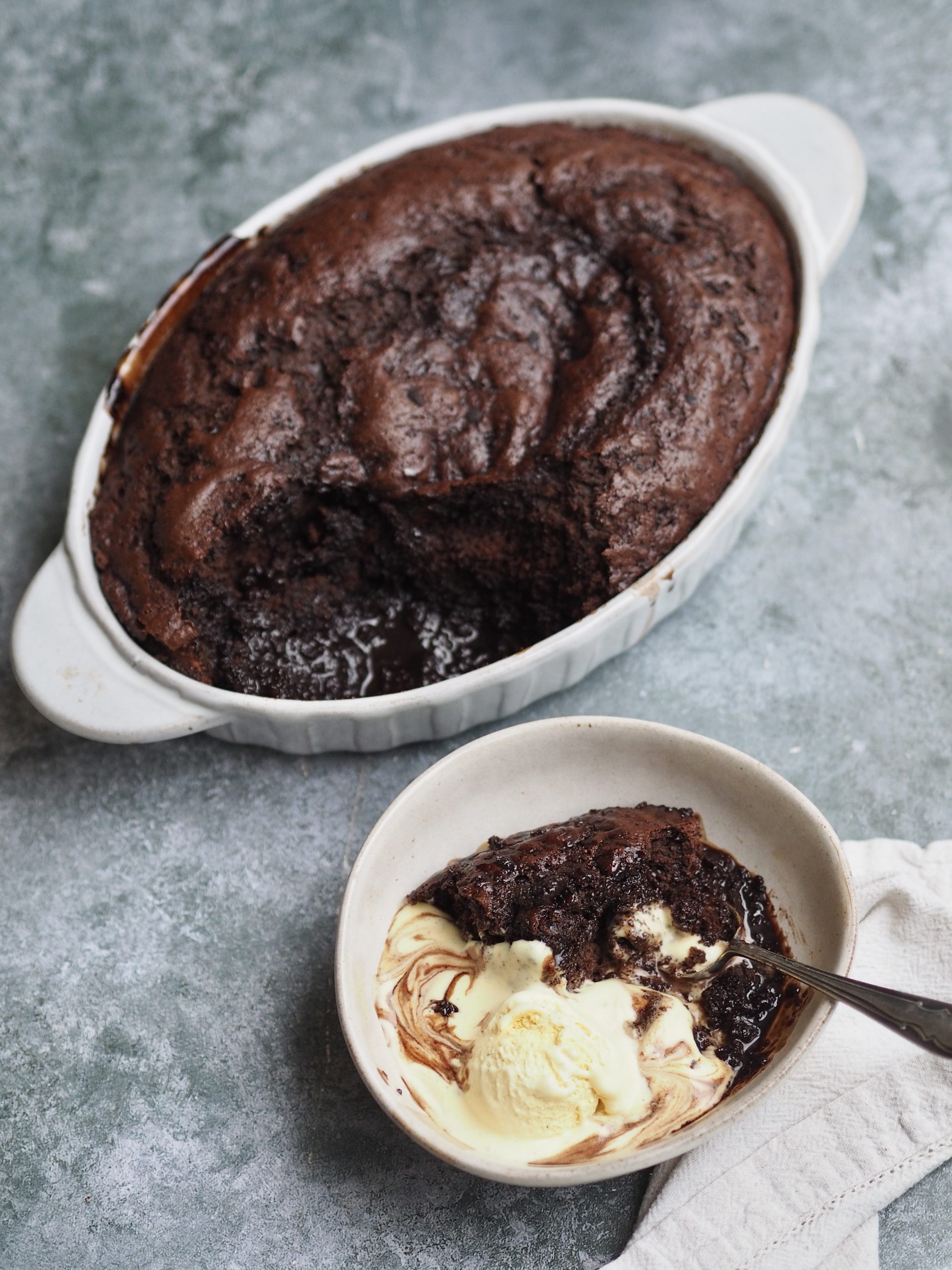 Self Saucing Chocolate Pudding scooped into a bowl with ice cream