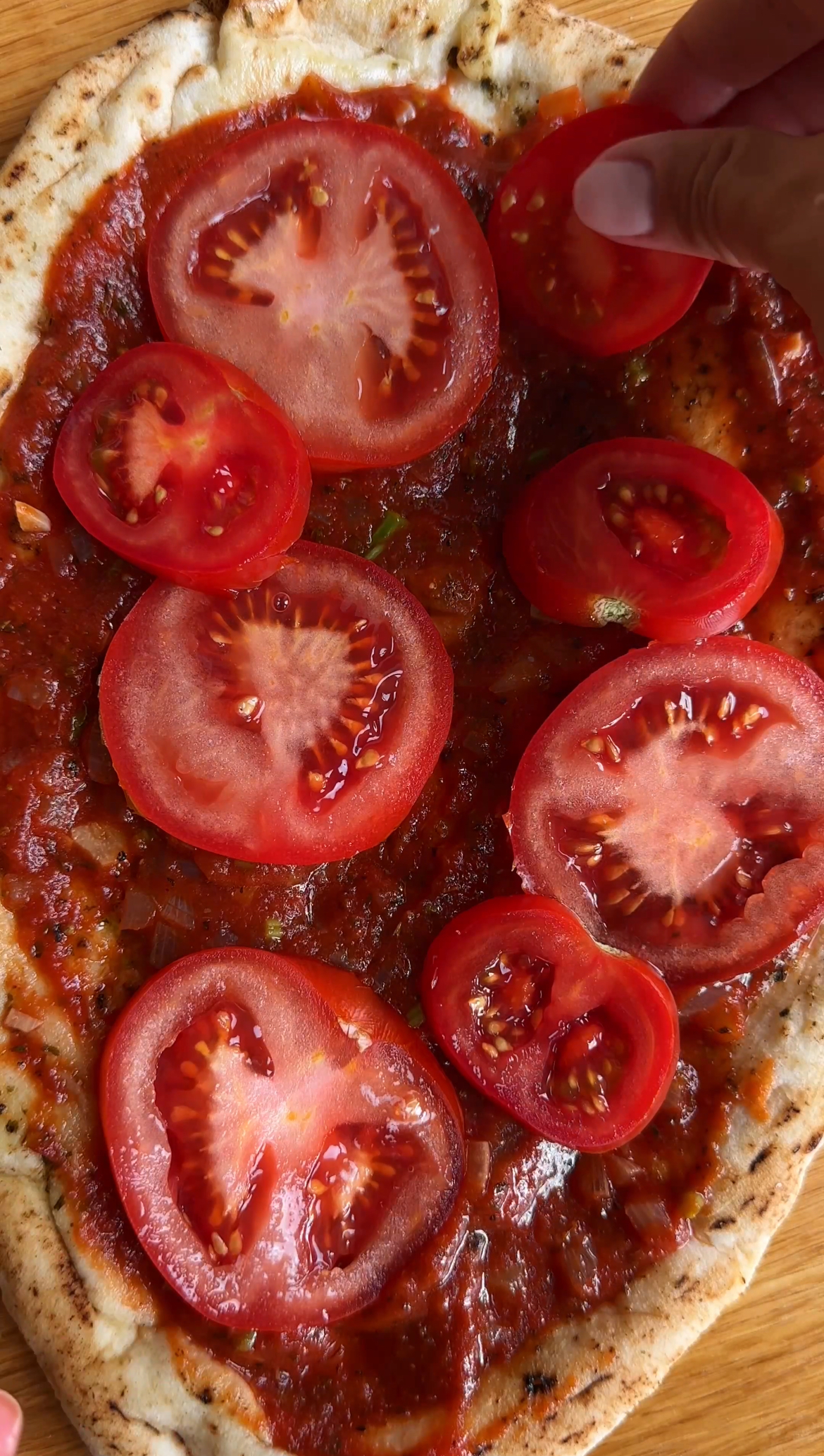 adding fresh tomatoes to flatbread pizza margherita