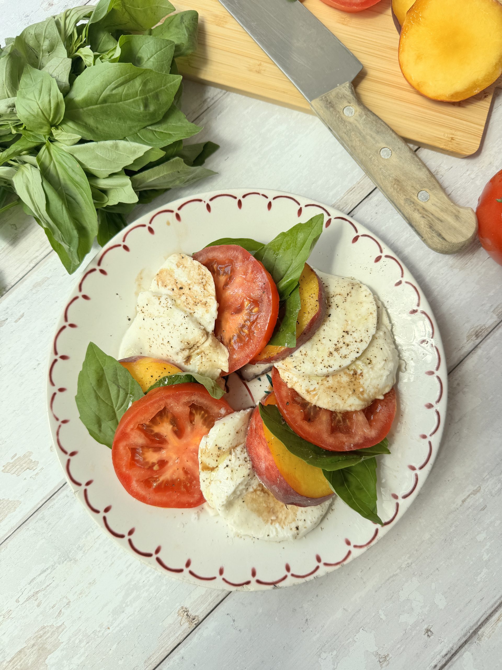 peach caprese on a white plate with red rim