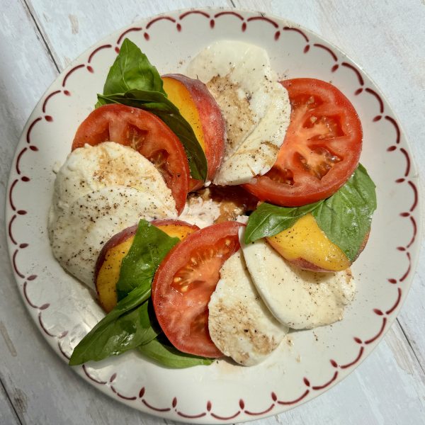 peach caprese on a white plate with red rim