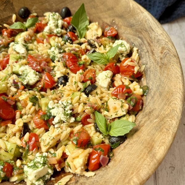 close up greek pasta salad in wooden bowl