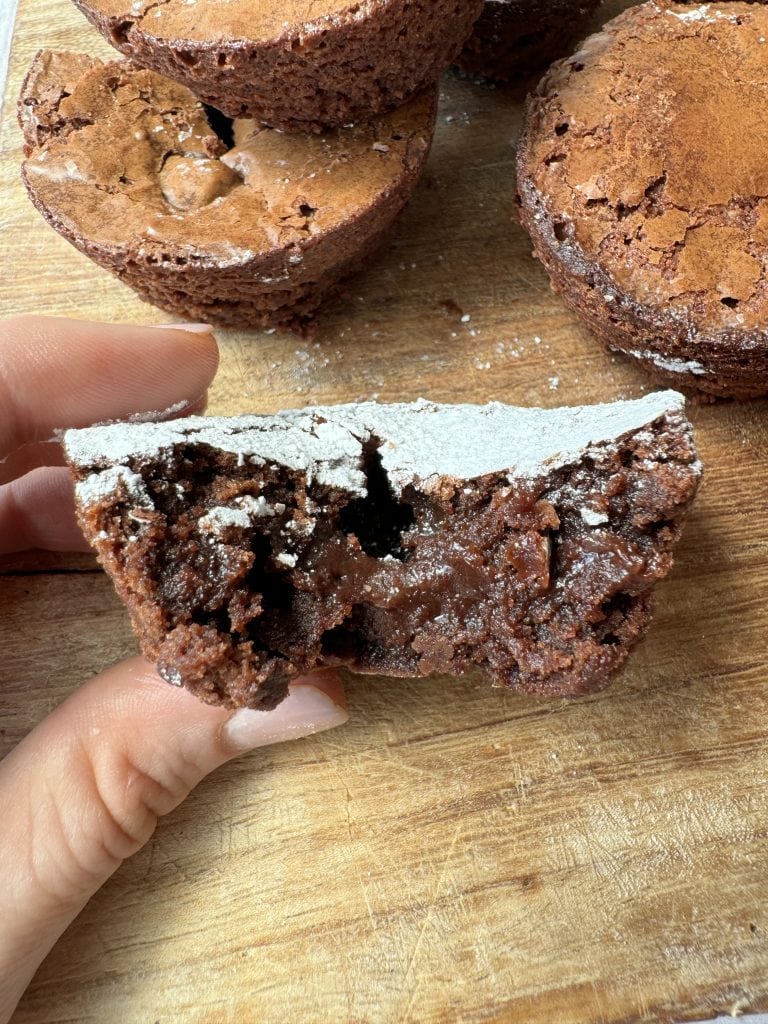 woman holding half a fudgy brownie bite